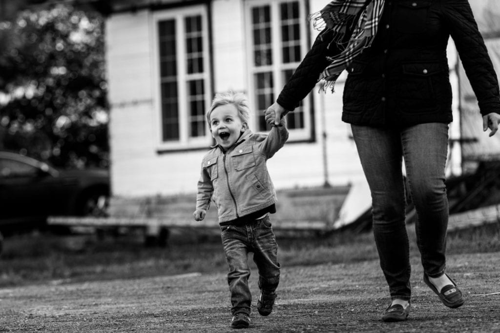 young boy running and laughing holding mom's hand in rural family shoot