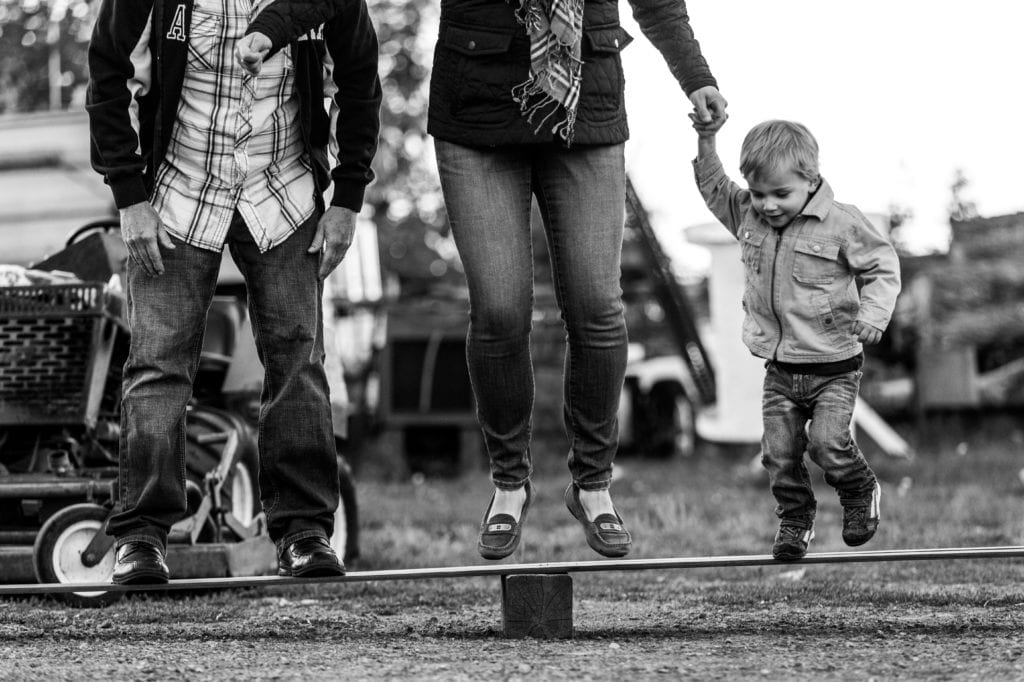 young boy and parents jumping on wooden board