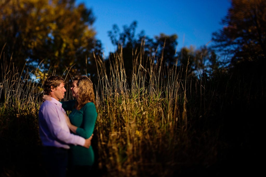 engaged couple in tall grass at sunset in Martintown