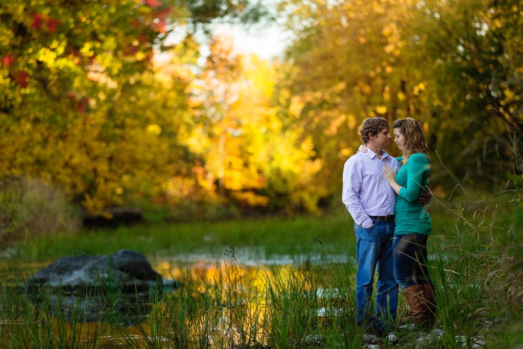 woman in bright green sweater and man in button up shirt in fall engagement session