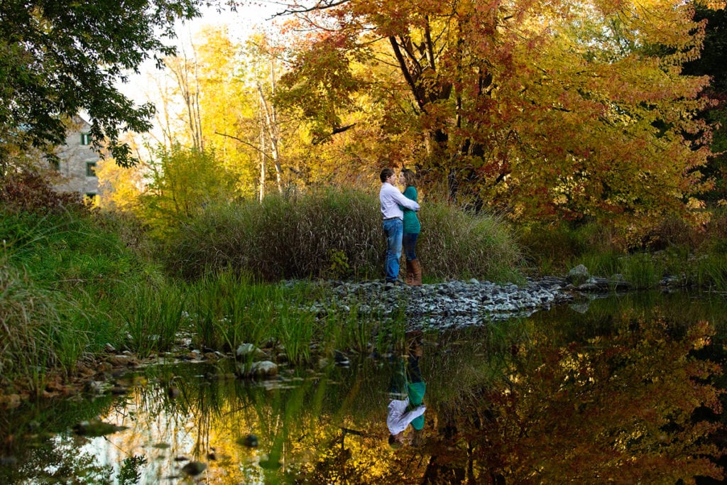 couple standing beside reflective pond in fall Martintown photo session