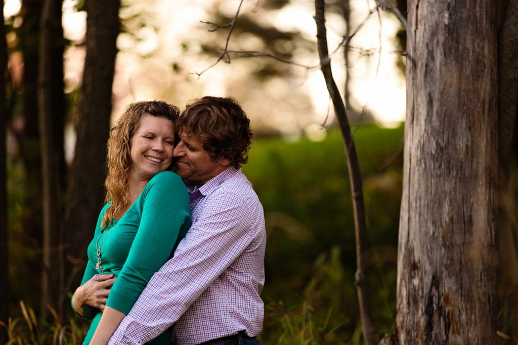 Smiling woman in bright green sweater and fiance in fall engagement session