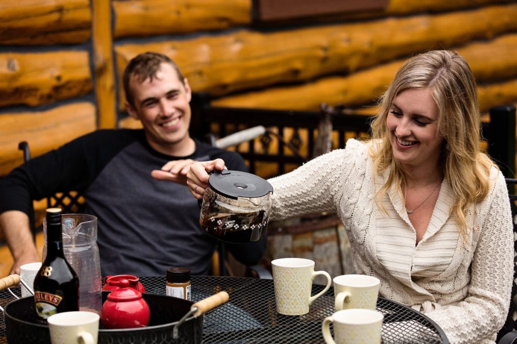 young woman pouring coffee while husband looks on smiling