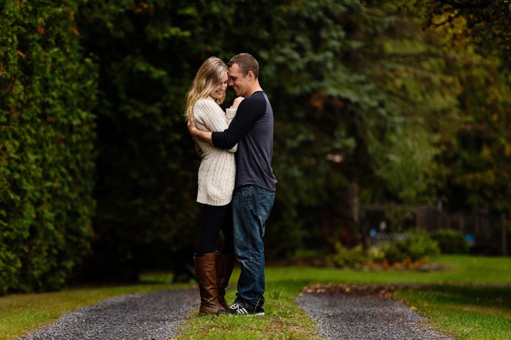 young couple cuddling on lush green path in rural ontario family session
