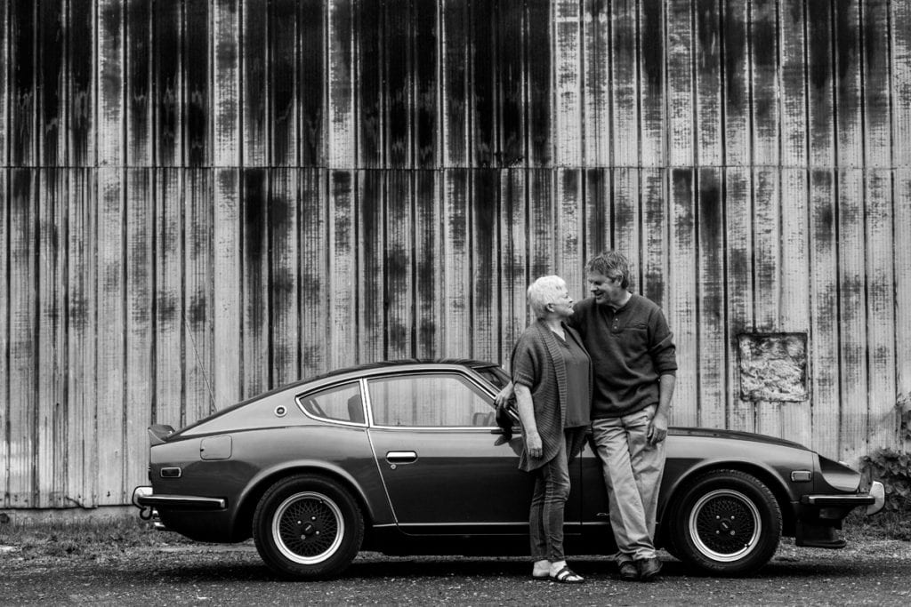 mature couple with rustic building background and classic car