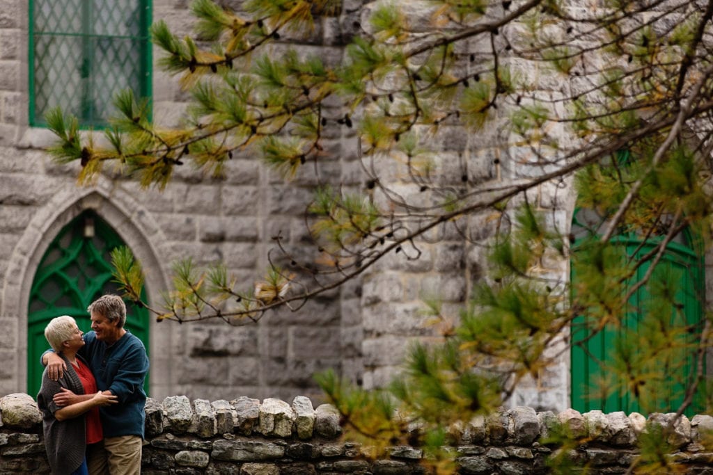Couple leaning on aged stone wall in front of church