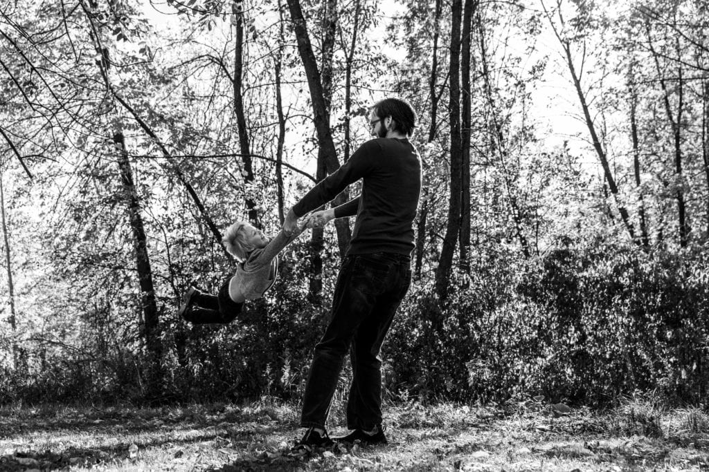dad twirling young boy in Candid Cornwall Family Portrait Session