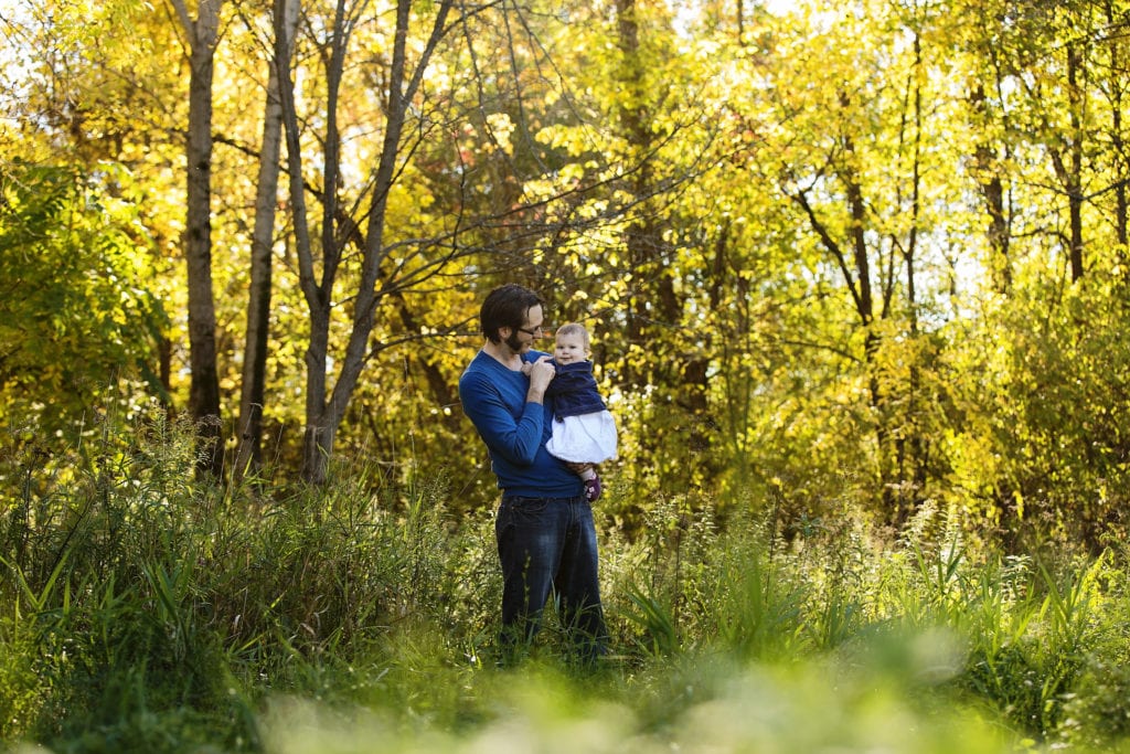 dad and baby daughter portrait in sunlit nature backdrop