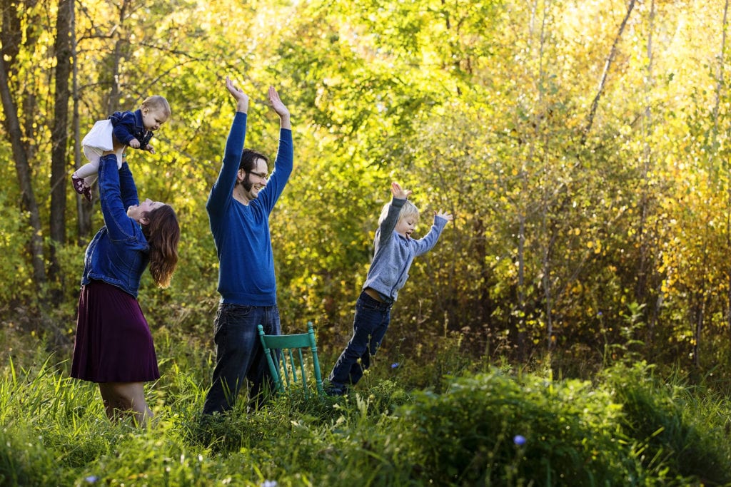 dad coaching young boy jumping off chair into grass during Candid Cornwall Family Portrait Session