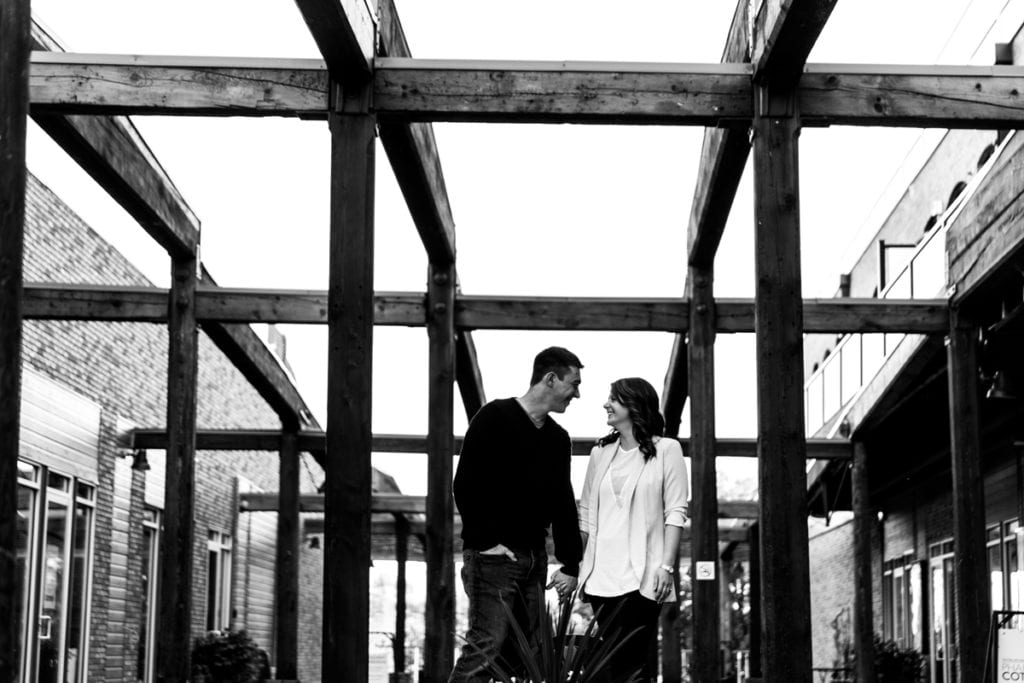couple holding hands under outdoor patio with large rustic beams