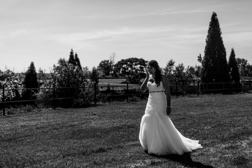 bride in fit and flare gown wipes tears while walking