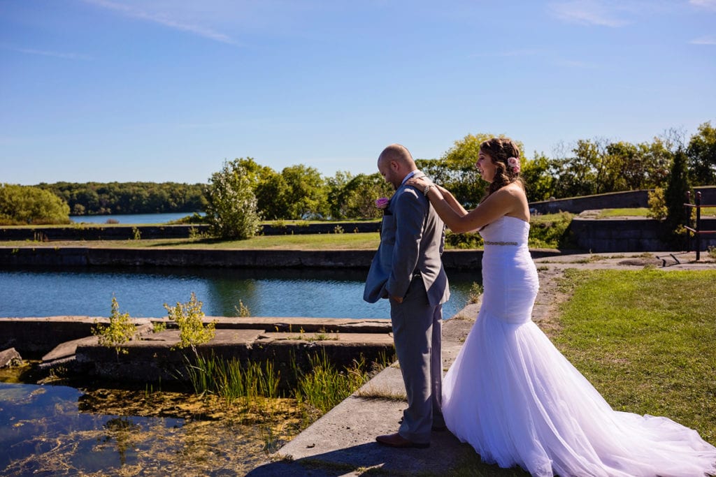 bride puts hands on groom's back during first look