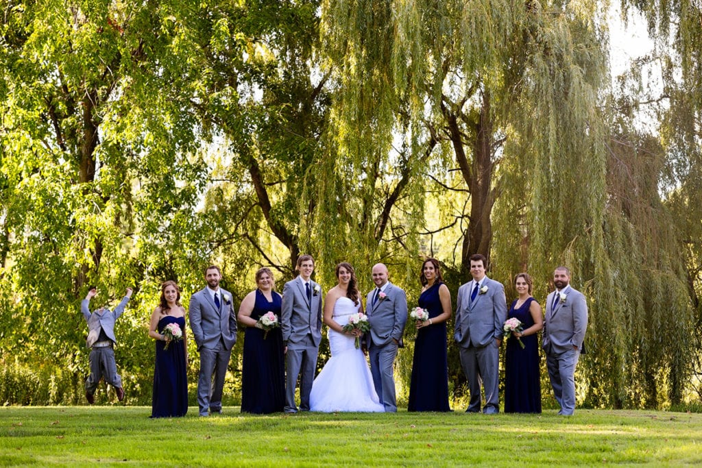 Cornwall wedding party poses while boy jumps