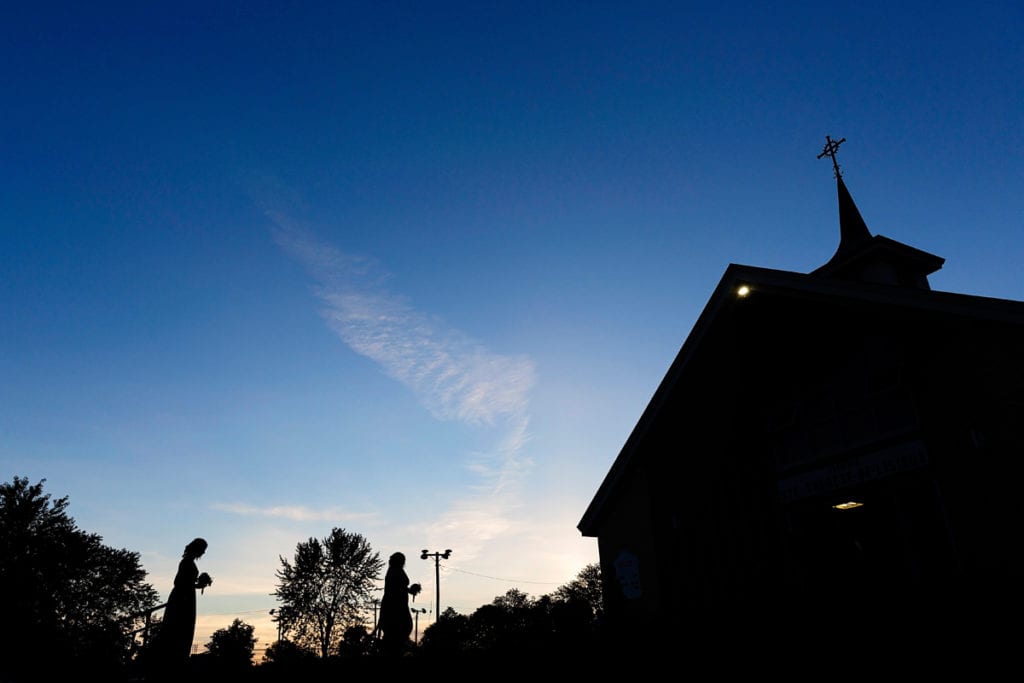 Bridesmaids walk to church at dusk for Cornwall evening wedding