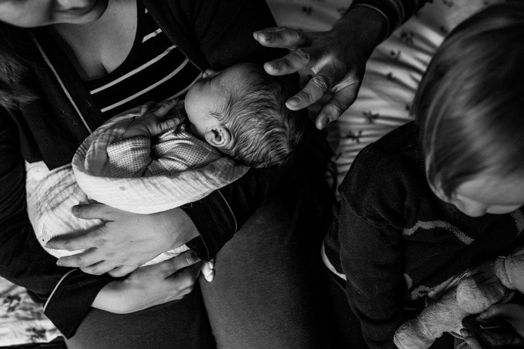 father reaching out to touch son's head while mother holds him