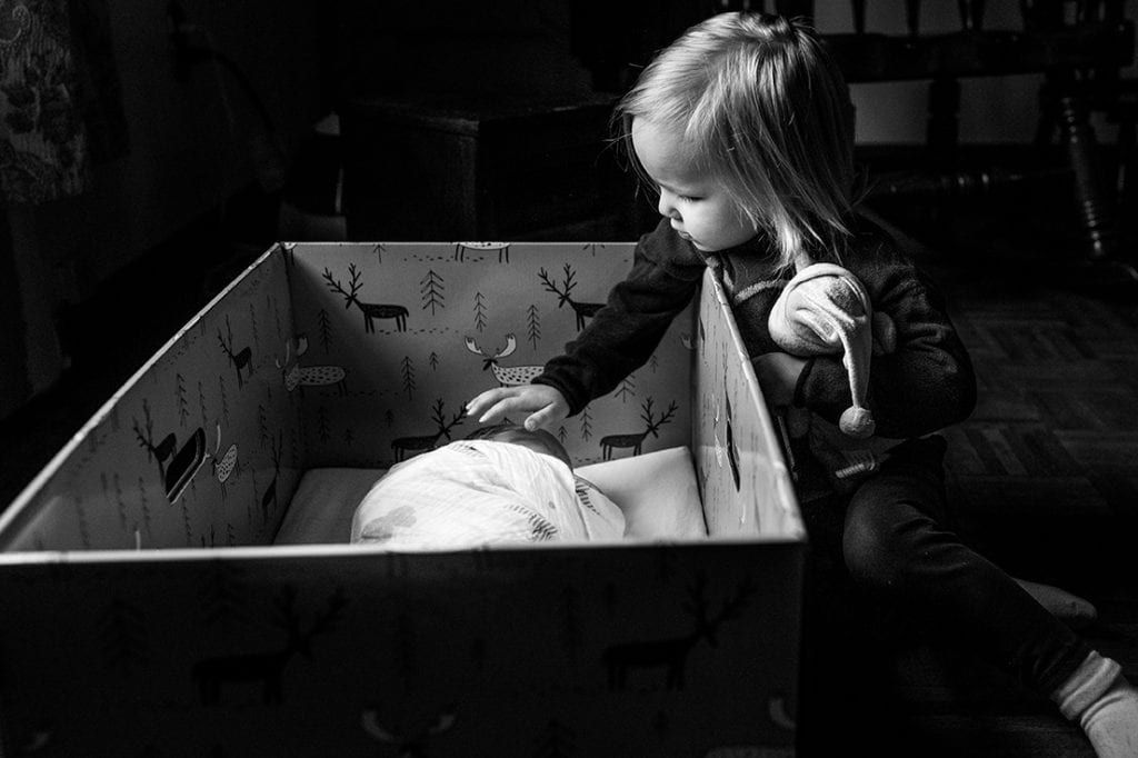 sister reaching out to touch baby brother