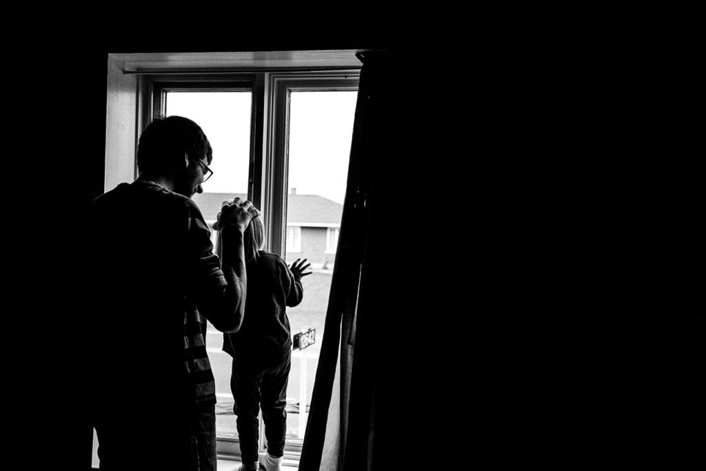 father and daughter looking out window