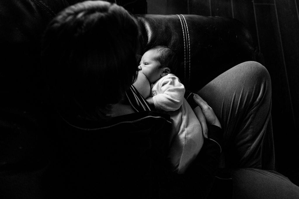mother breastfeeding in window light