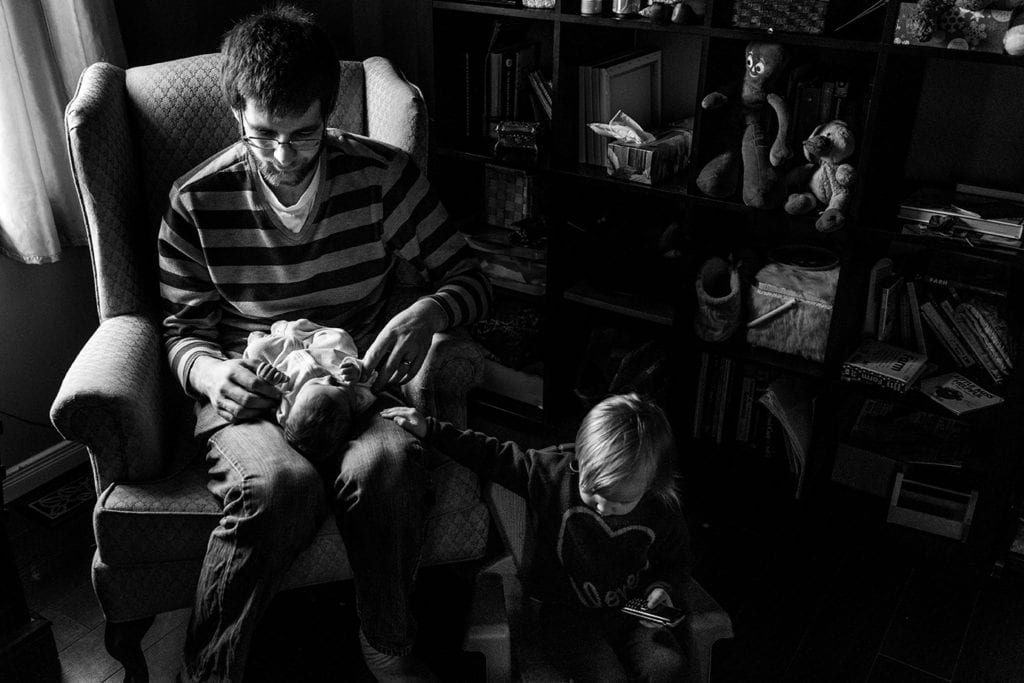 daughter touching father's leg while he holds son