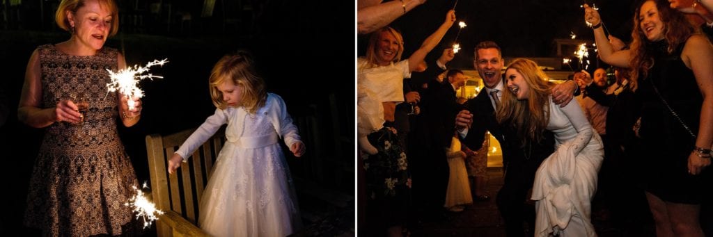 Little girl plays with sparkler while bride and groom make a sparkler tunnel exit during reception at Rhinefield House