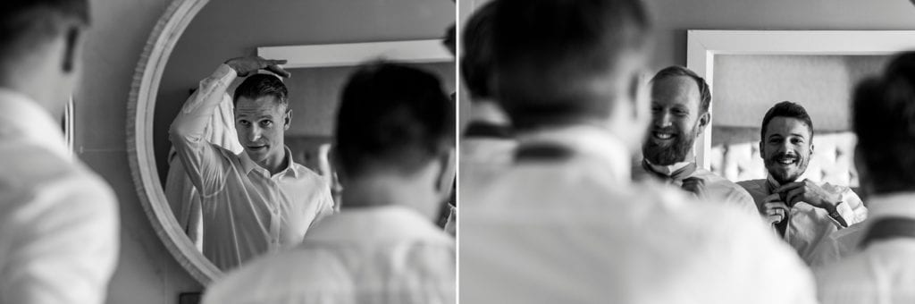 groomsmen and groom use mirror to help tie ties and fix hair during groom prep at Christchurch Habour Hotel & Spa