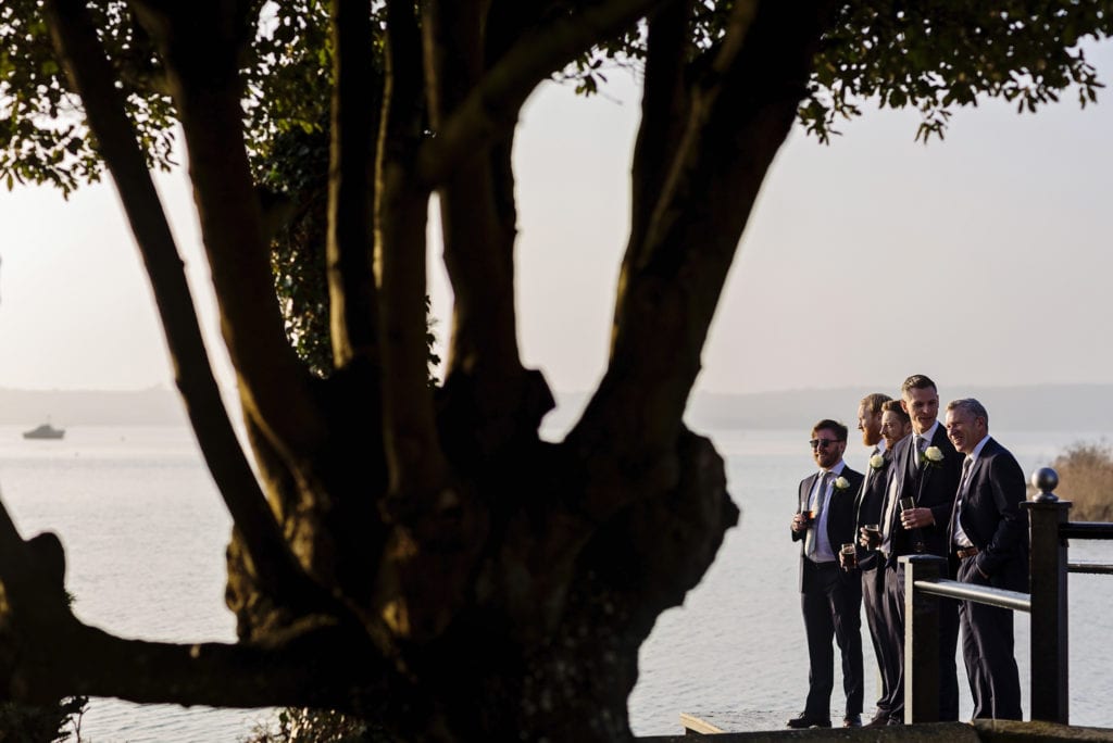 groom stands with ushers and father on dock during groom prep at Christchurch Habour Hotel & Spa