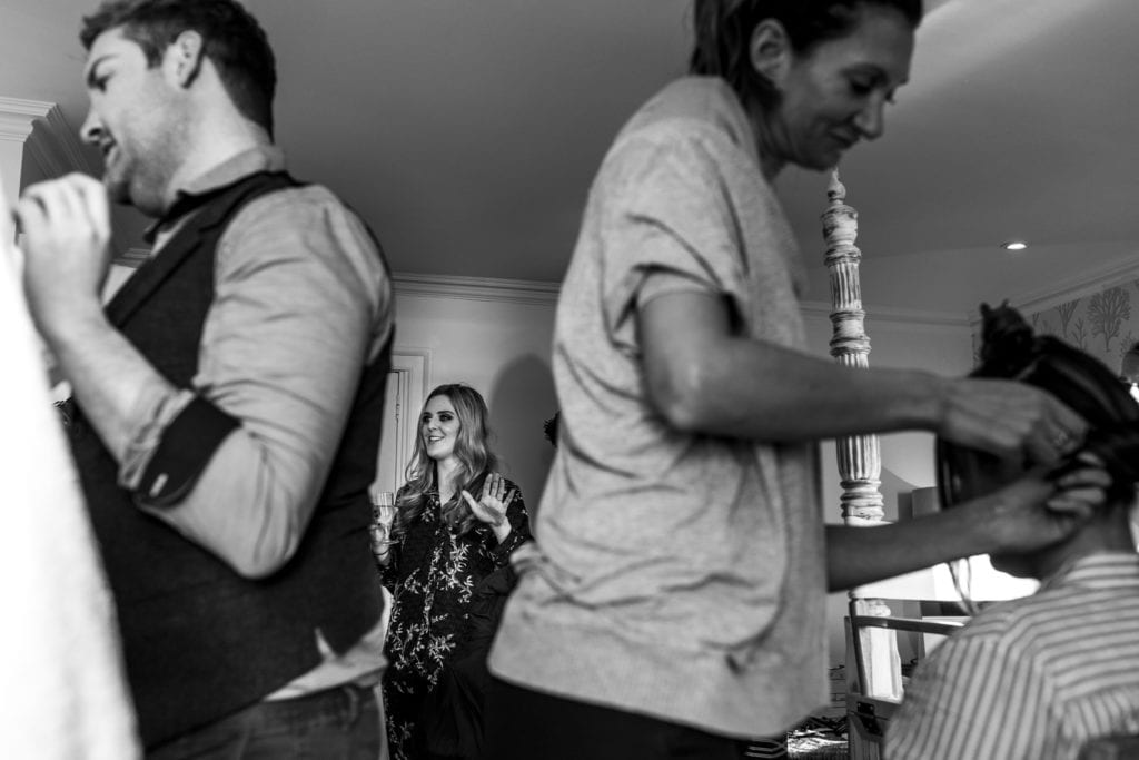 hair and makeup artists work on bridesmaids while framing bride in background during bridal prep at Christchurch Habour Hotel & Spa