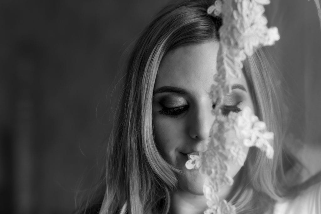 bride holds lace detail from veil in front of her face during bridal prep at Christchurch Habour Hotel & Spa