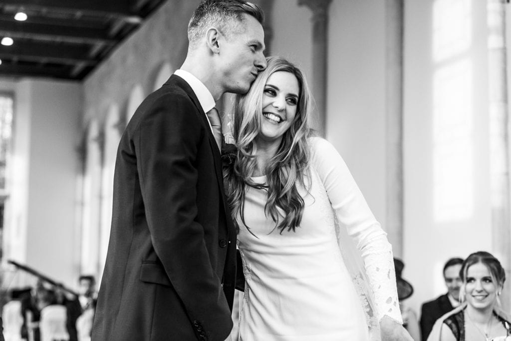 groom kisses bride on head after first kiss during chic New Forest wedding at Highcliffe Castle