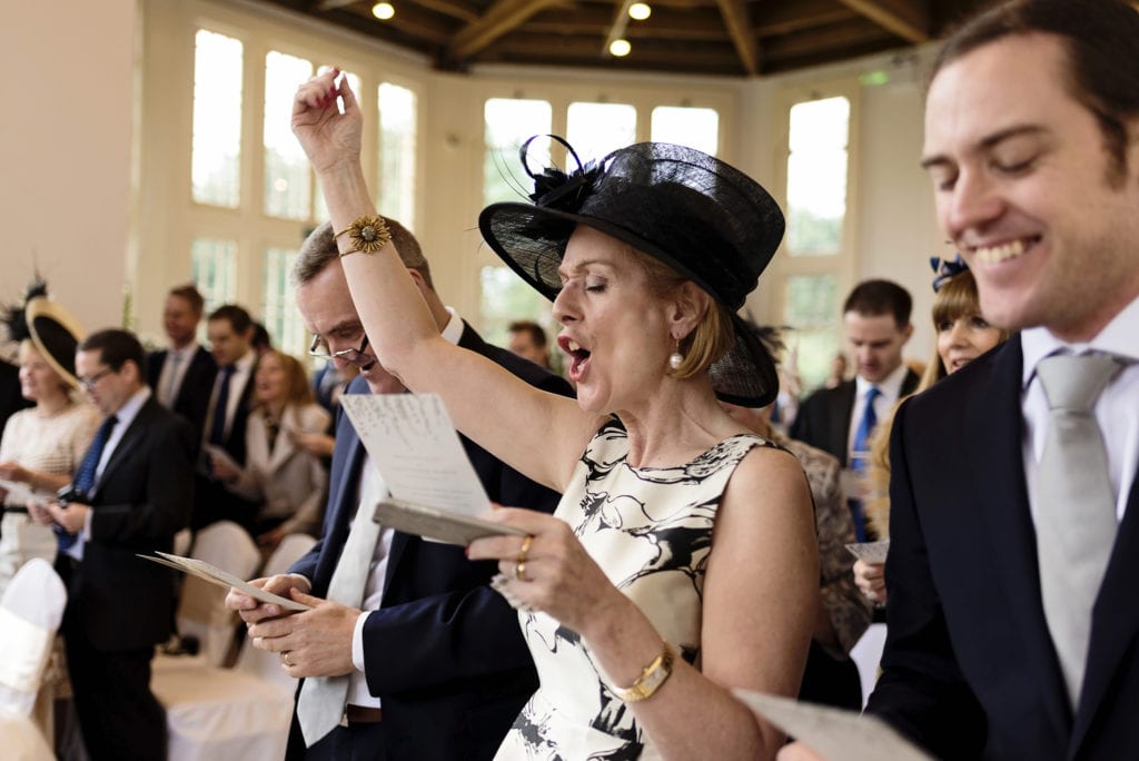mother of the bride sings enthusiastically during Highcliffe Castle wedding ceremony