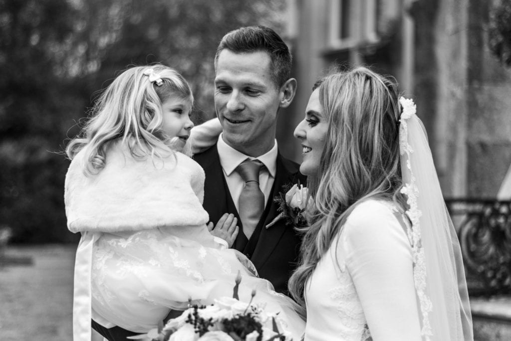 bride and groom with flower girl in groom's arms after Highcliffe Castle wedding ceremony