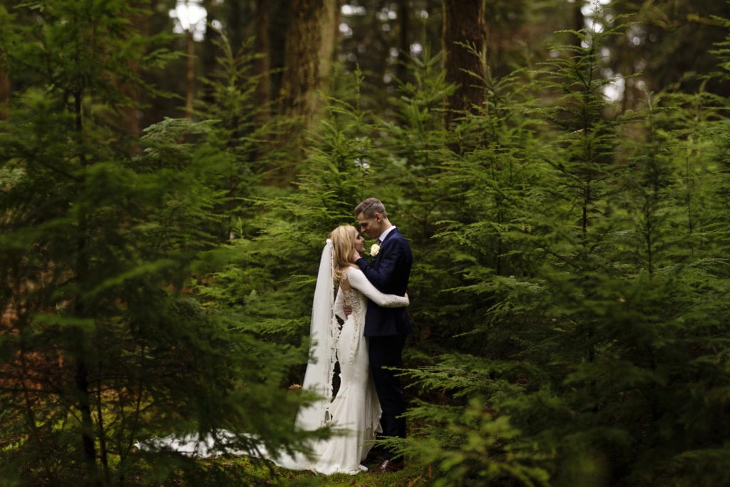 Brenizer Method portrait of groom holding bride's face in pine grove on Rhinefield Ornamental Drive during New Forest wedding portraits