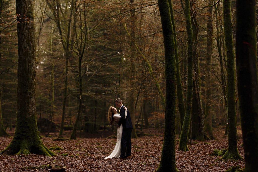 bride and groom cuddle amongst tall trees on Rhinefield Ornamental Drive during chic New Forest wedding portraits