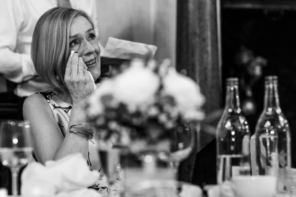 mother of the bride looks up and wipes tears away during wedding reception at Rhinefield House