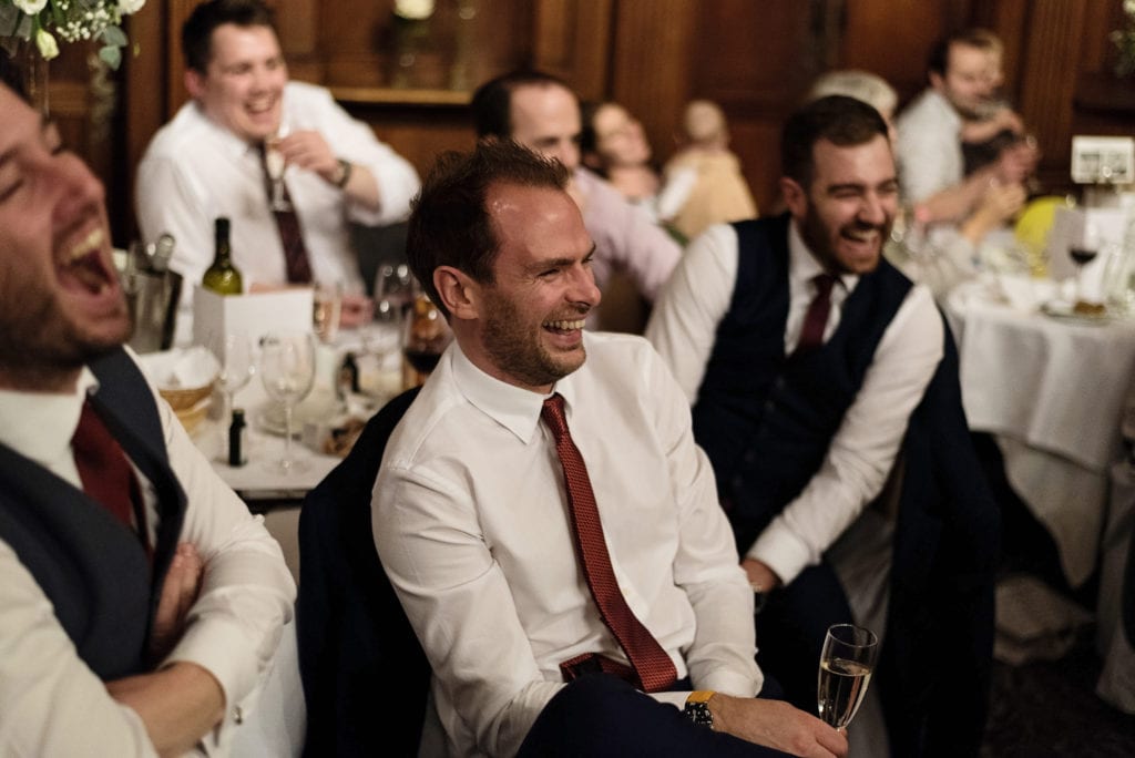 group of men laugh enthusiastically during wedding reception at Rhinefield House