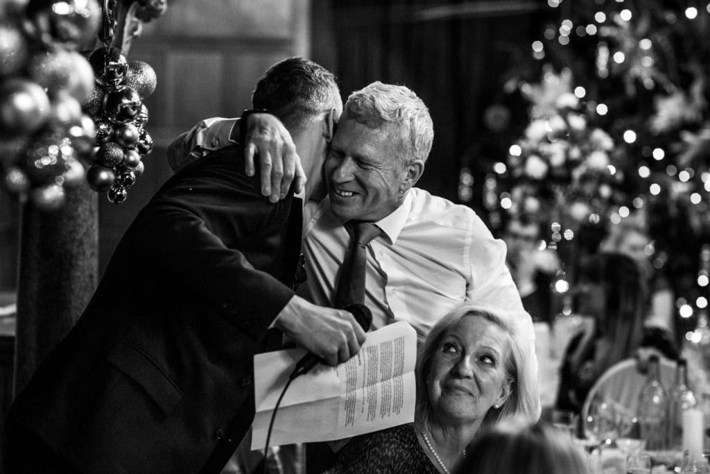 groom hugs father of the bride after speech during wedding reception at Rhinefield House
