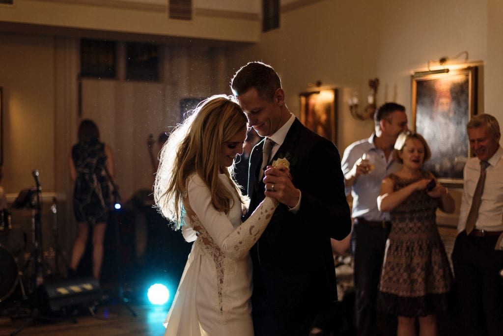 Groom holds bride close during slow dance at start of evening wedding reception at Rhinefield House