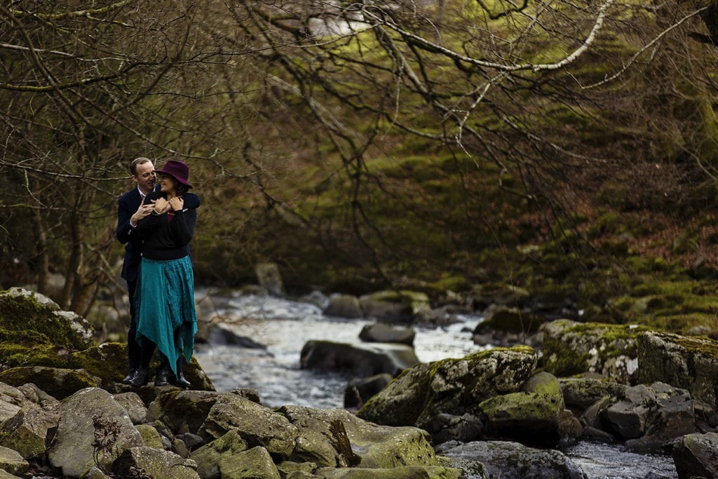 couple cuddle next to Llanberis river during Snowdonia portrait session