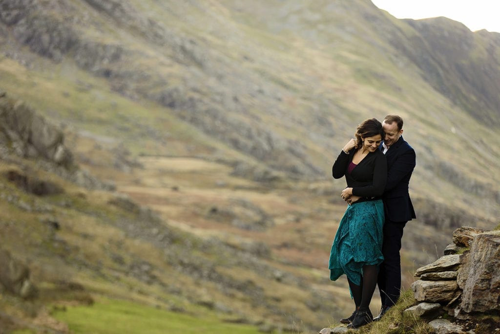 woman holds hair out of face while husband holds her during Snowdonia portrait session