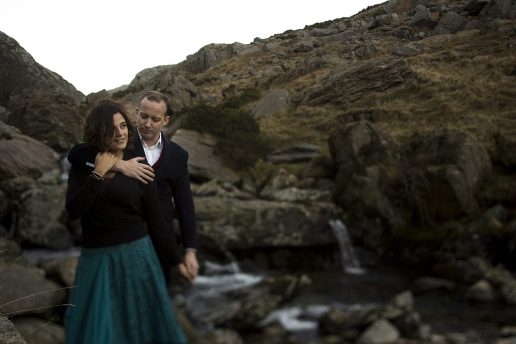 man holds wife next to river during Snowdonia portrait session