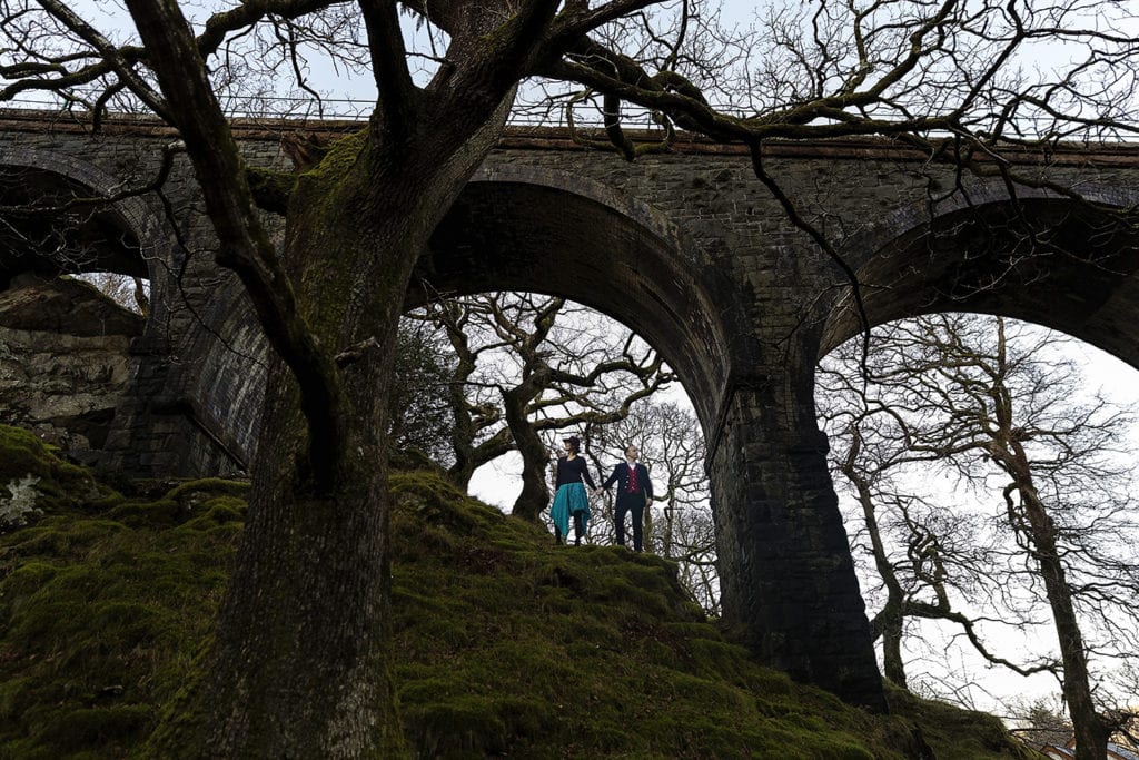 man and woman look opposite directions while standing under a viaduct during Snowdonia portrait session
