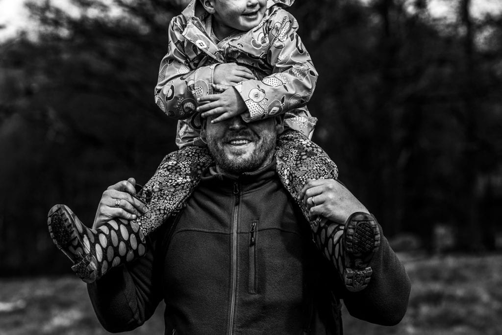 girls covers dad's face while riding on his shoulders