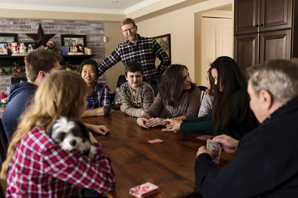 large family gathers around kitchen table to play cards
