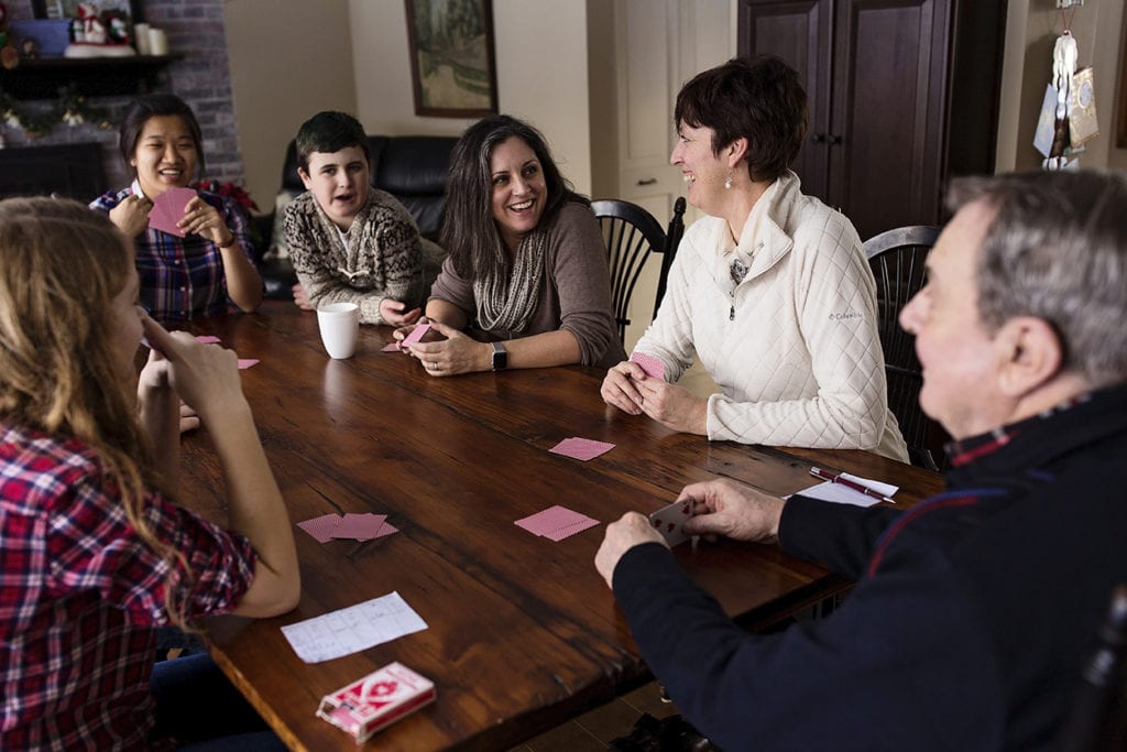 family sitting at kitchen table with red playing cards