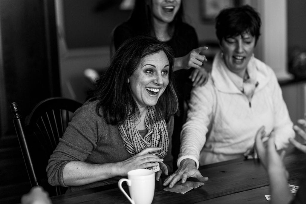 sisters laugh together at kitchen table while playing cards