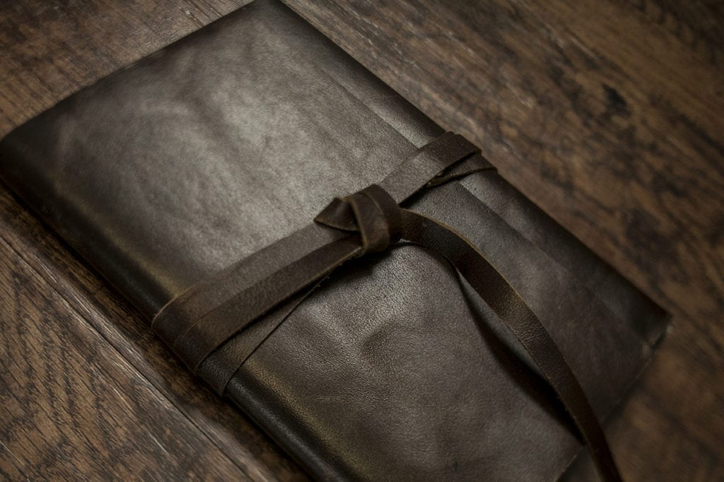 leather strap wrapped around dark leather photo holding modern ontario wedding photos