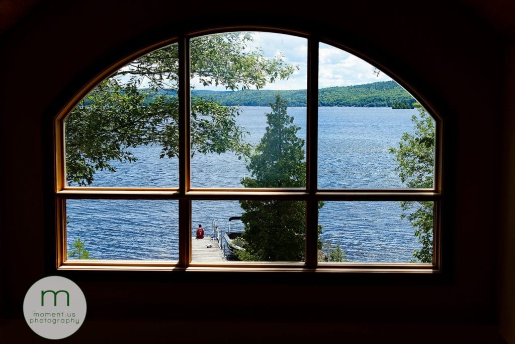 Man sits at end of dock surrounded by trees and framed in large semi-circular window