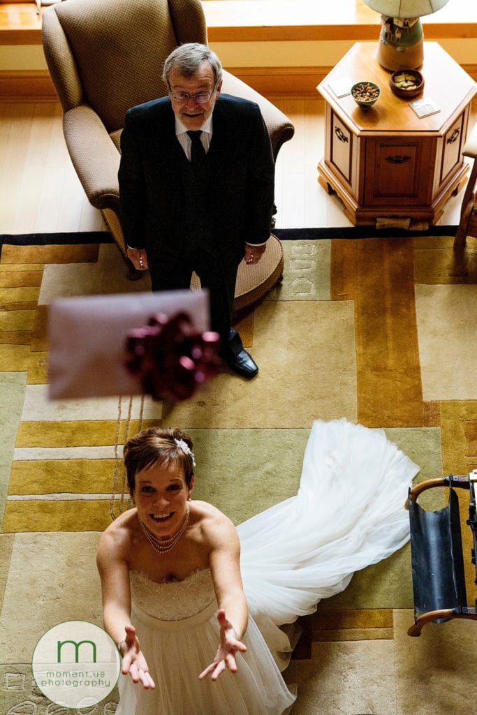 bride catches envelope being dropped from balcony while father looks on