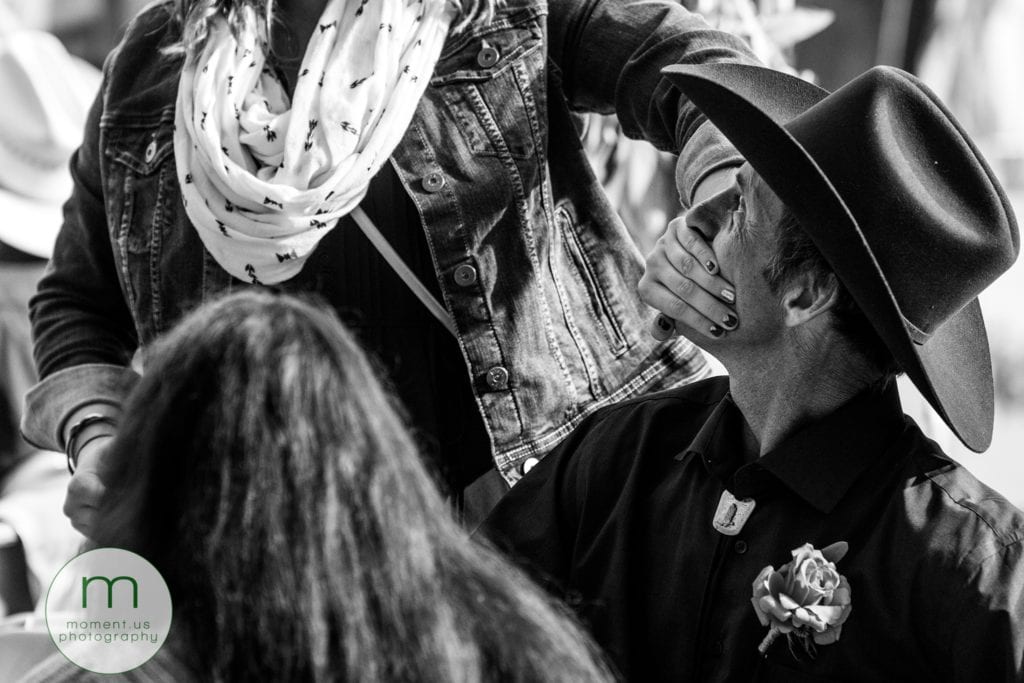 woman puts hand over man's mouth during wedding reception