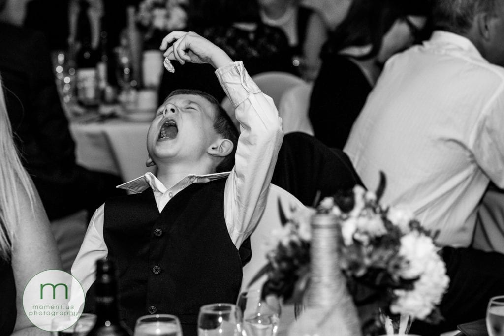child dangles gum over his mouth during wedding reception